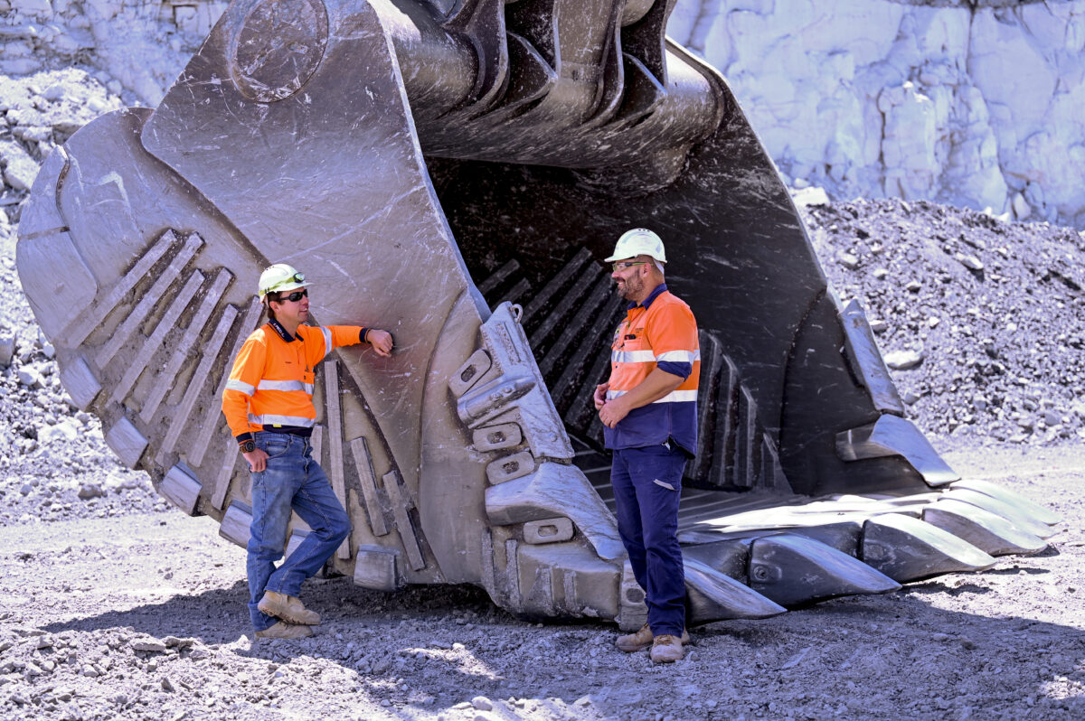 Two MEU members next to a large coal digger
