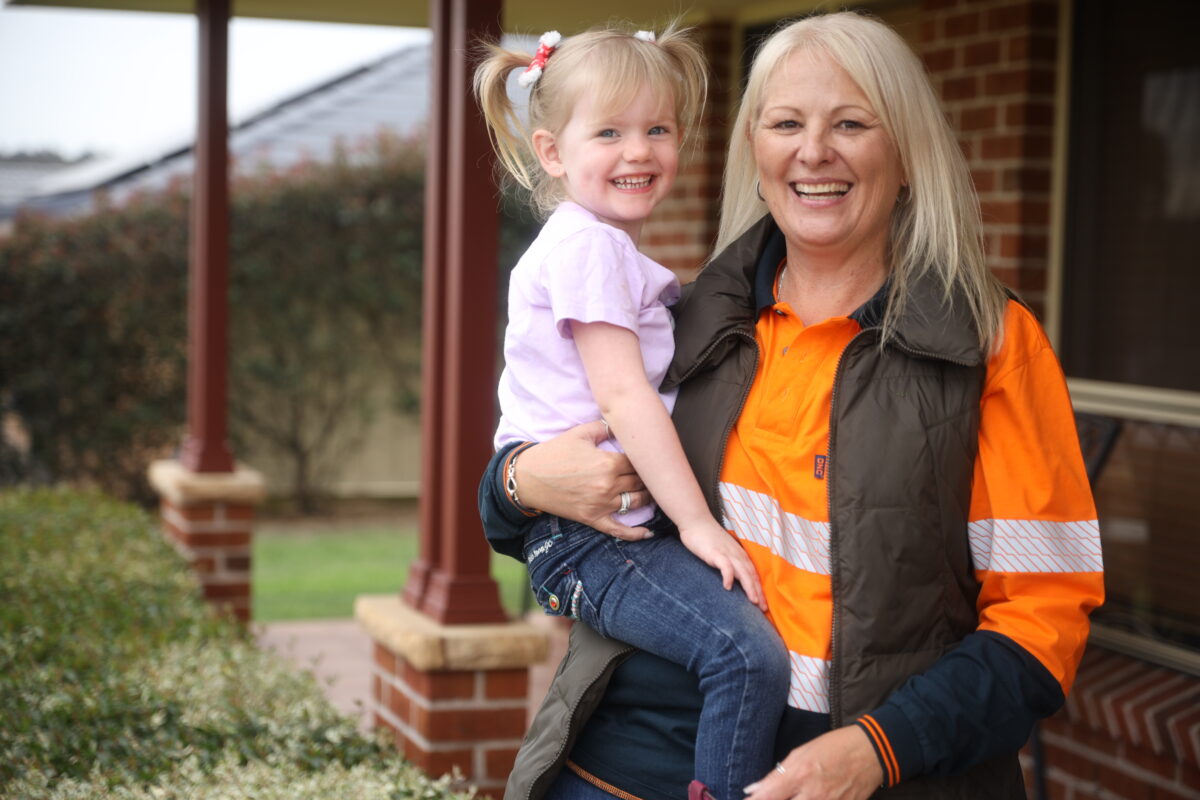 A female MEU member smiling while holding a young child