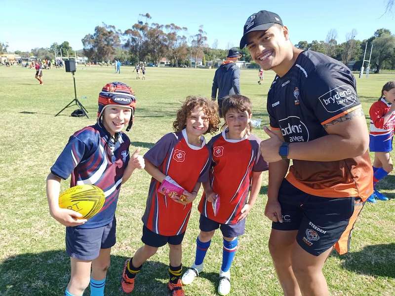 Tigers player Tommy Talau poses with children playing rugby leage