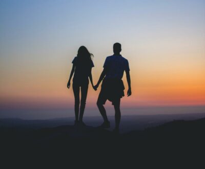 Heterosexual couple - man and woman couple walk on the beach at sunset