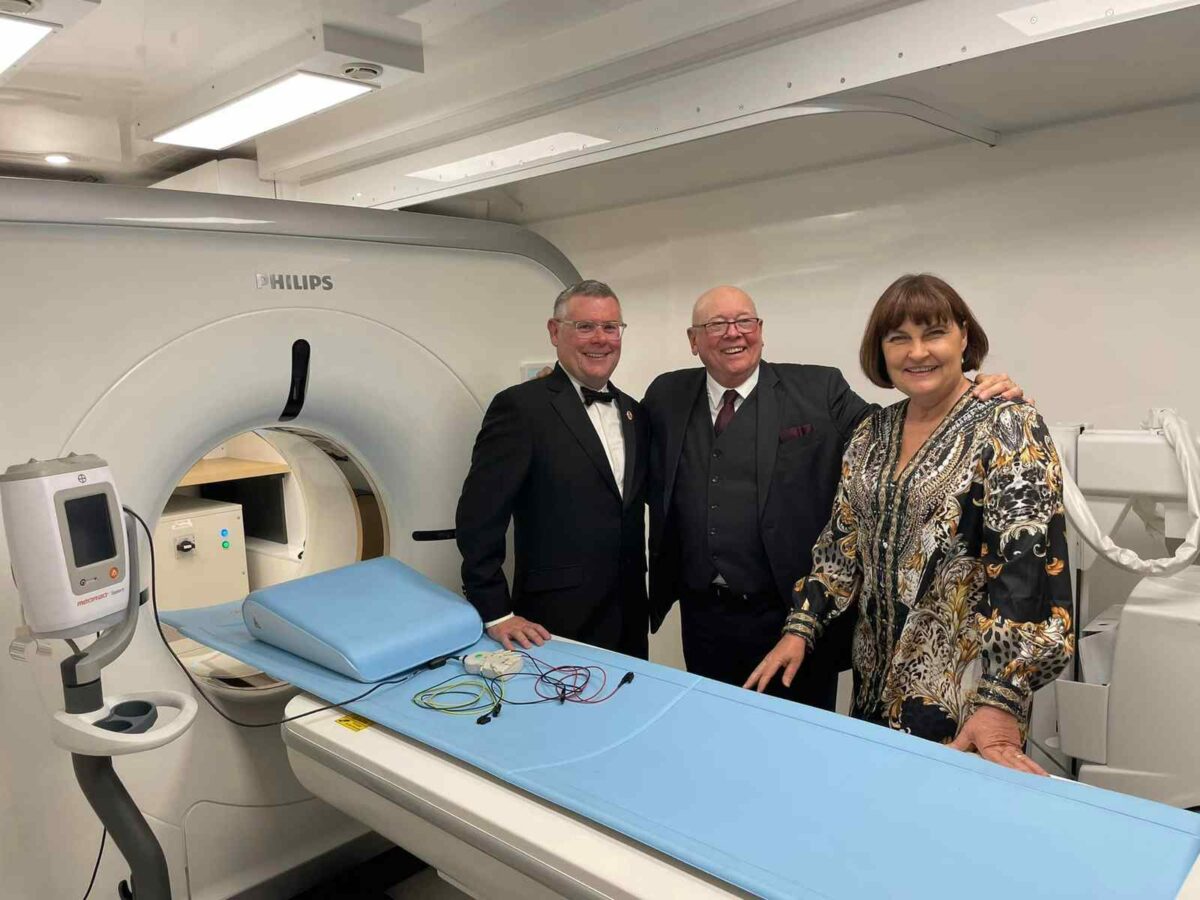 3 people standing in front of an MRI machine