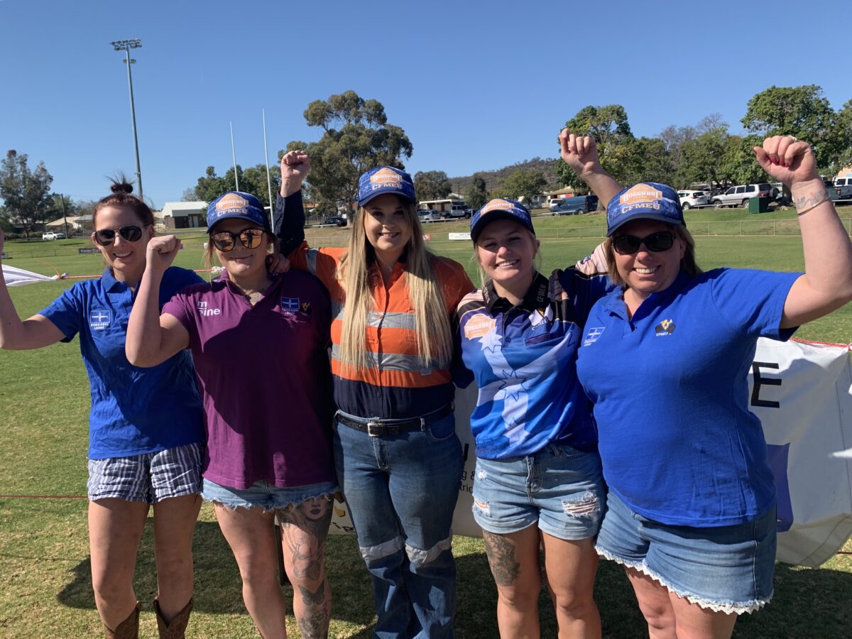 5 women miners standing with fist raised