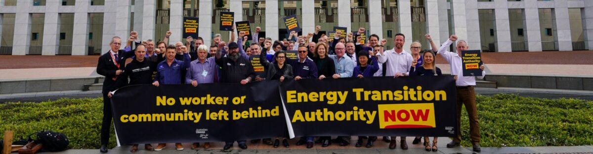 People holding banners outside the Parliament building in Canberra that read 'no worker or community left behind' and Energy transition Authority NOW'
