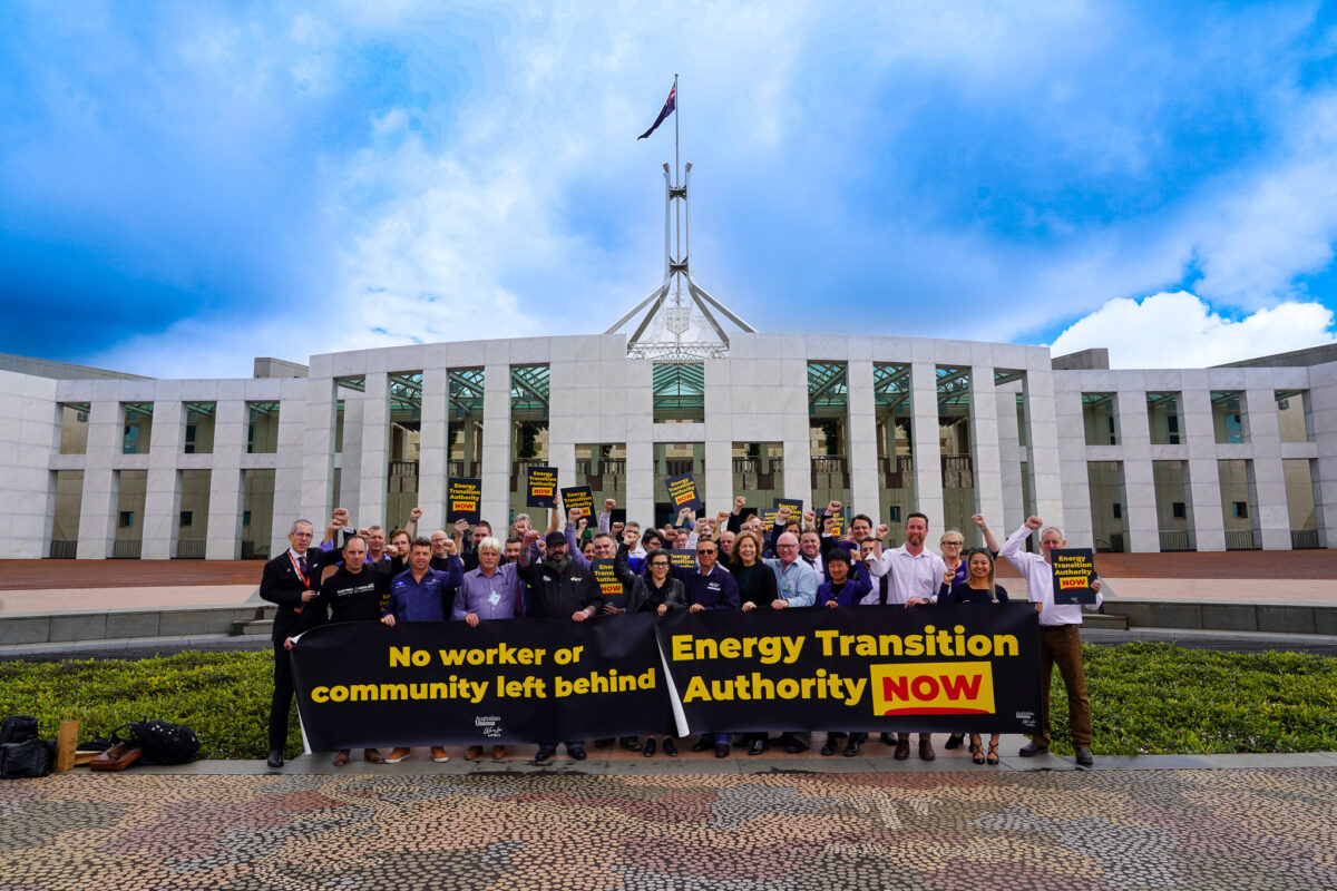 People holding banners outside the Parliament building in Canberra that read 'no worker or community left behind' and Energy transition Authority NOW'
