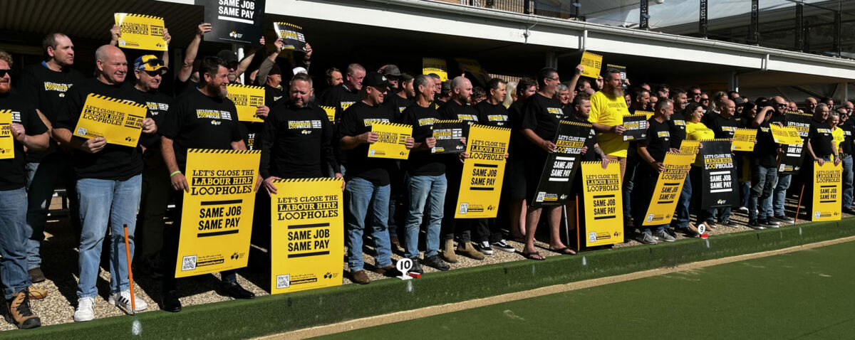 Group of Mining and Energy members stood on a lawn bowls lawn outside a bowling club holding Same Job Same Pay corflutes