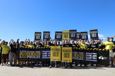 MEU Members in Rockhampton standing in front of corflutes and banners with the text: message 'Same Job Same Pay - Close Labour Hire Loopholes'