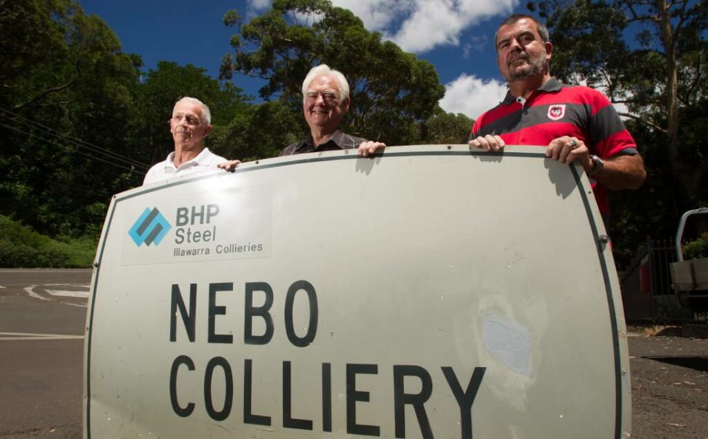 Roy Gersbach stands in between two people behind a sign for Nebo Colliery