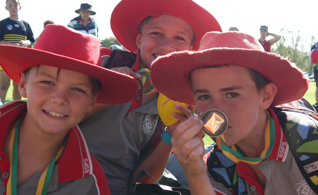Three young boys in red hats showing the medals they won at the coal miners cups