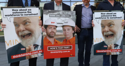 A group of unionists holding placards reading "Same Job. Less Pay. How is that fair?"